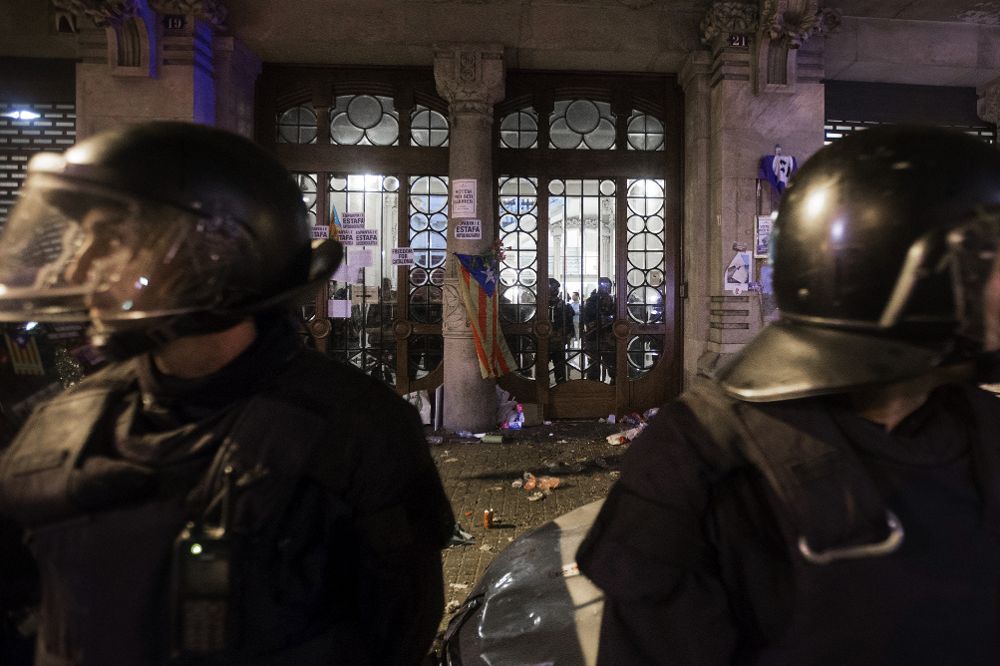 Agentes de los Mossos d'Esquadra custodian las puertas de la sede de la consellería de Economía de la Generalitat.