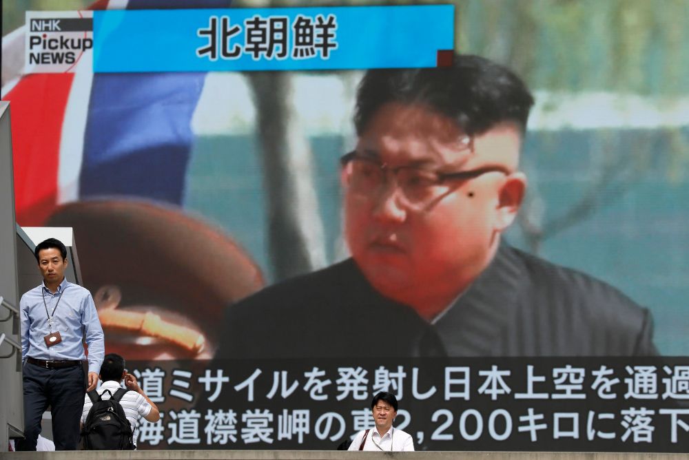 Los peatones caminan bajo un monitor a gran escala que muestra al líder norcoreano Kim Jong-un.