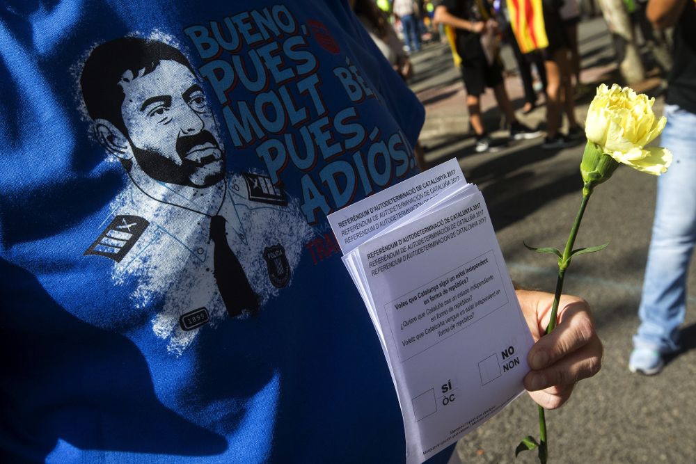 Una persona con la camiseta del major de los Mossos, Josep Lluis Trapero, y papeletas del referéndum.