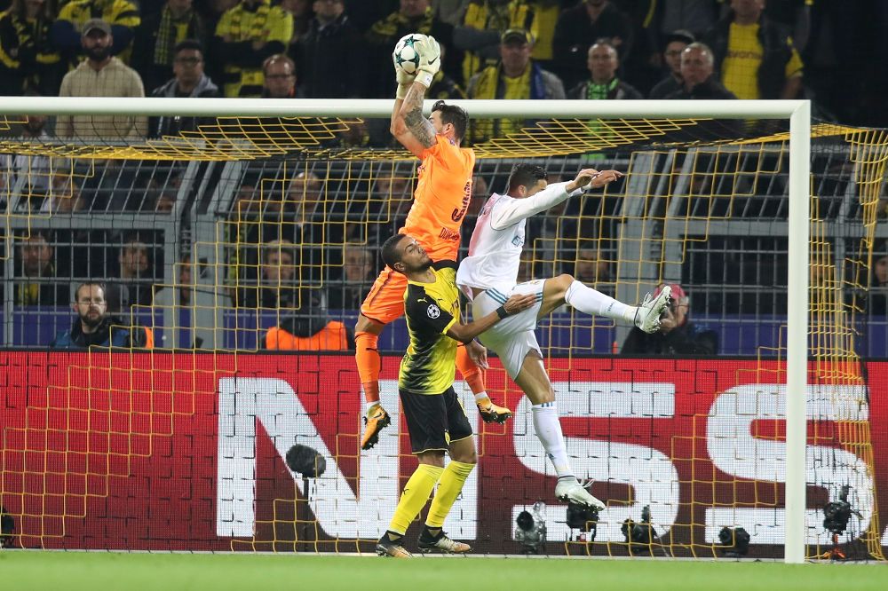 El arquero de Dortmund Roman Buerki (i) atrapa un balón ante Cristiano Ronaldo (d) de Real Madrid.