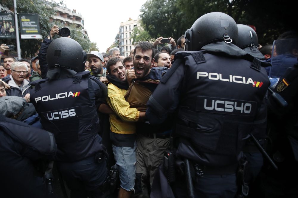 Agentes antidisturbios de la Policía Nacional forman un cordón de seguridad frente al colegio Ramón Llull de Barcelona.