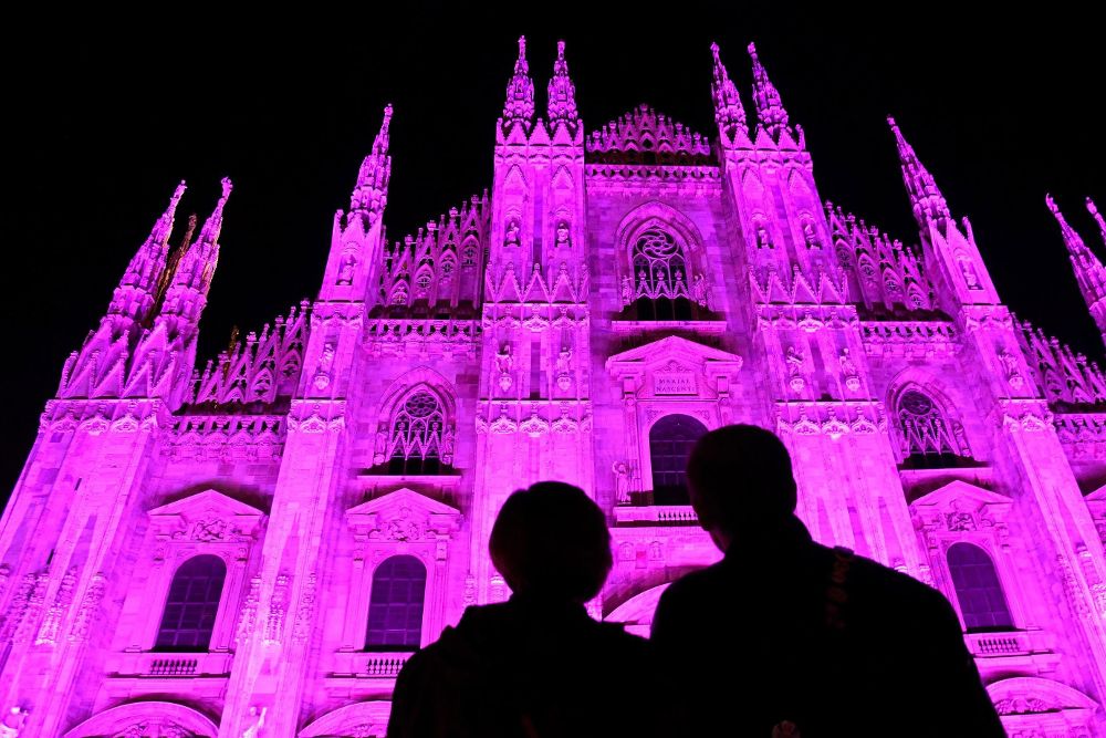Una pareja observa la Catedral de Milán iluminada de rosa para conmemorar el aniversario 25 de la lucha contra el cáncer de seno.