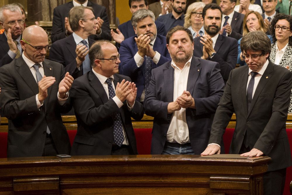 El presidente de la Generalitat, Carles Puigdemont (d), recibe el aplauso de los miembros del del Govern tras su comparecencia hoy en el Parlament.