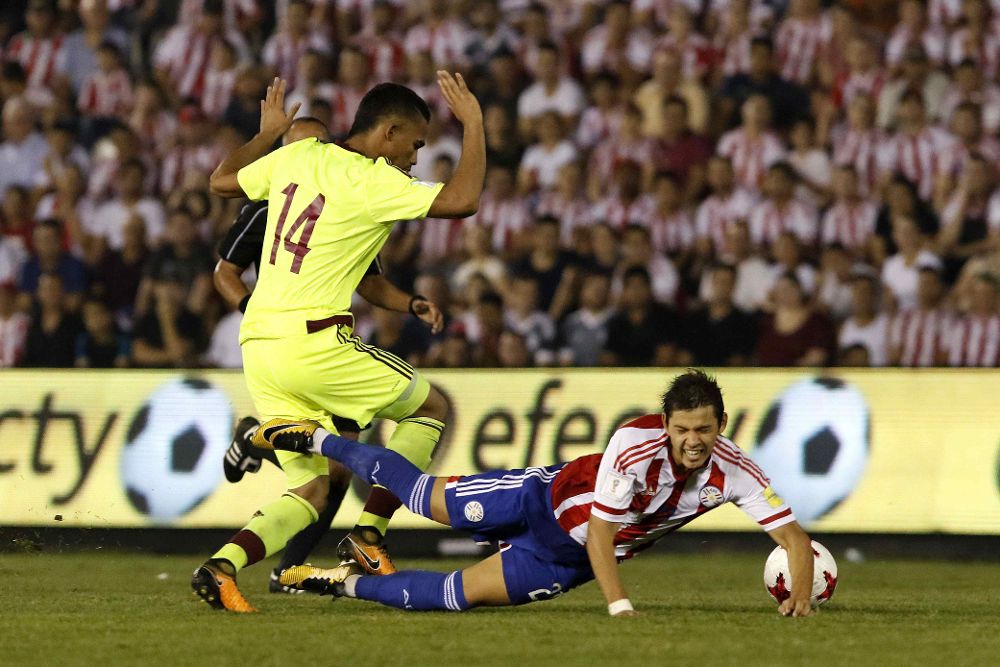 El jugador de la selección paraguaya Oscar Romero (d) disputa un balón frente al jugador de la selección venezolana Yangel Herrera (i).