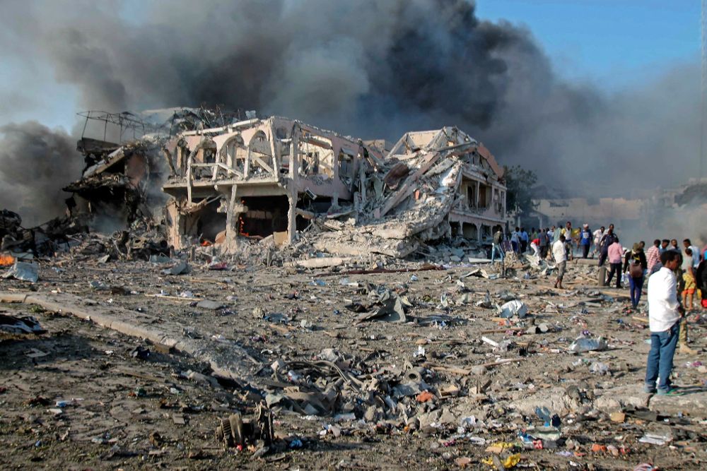 Varias personas deambulan alrededor de los restos de un hotel de Mogadiscio junto al cual explotó uno camión bomba.