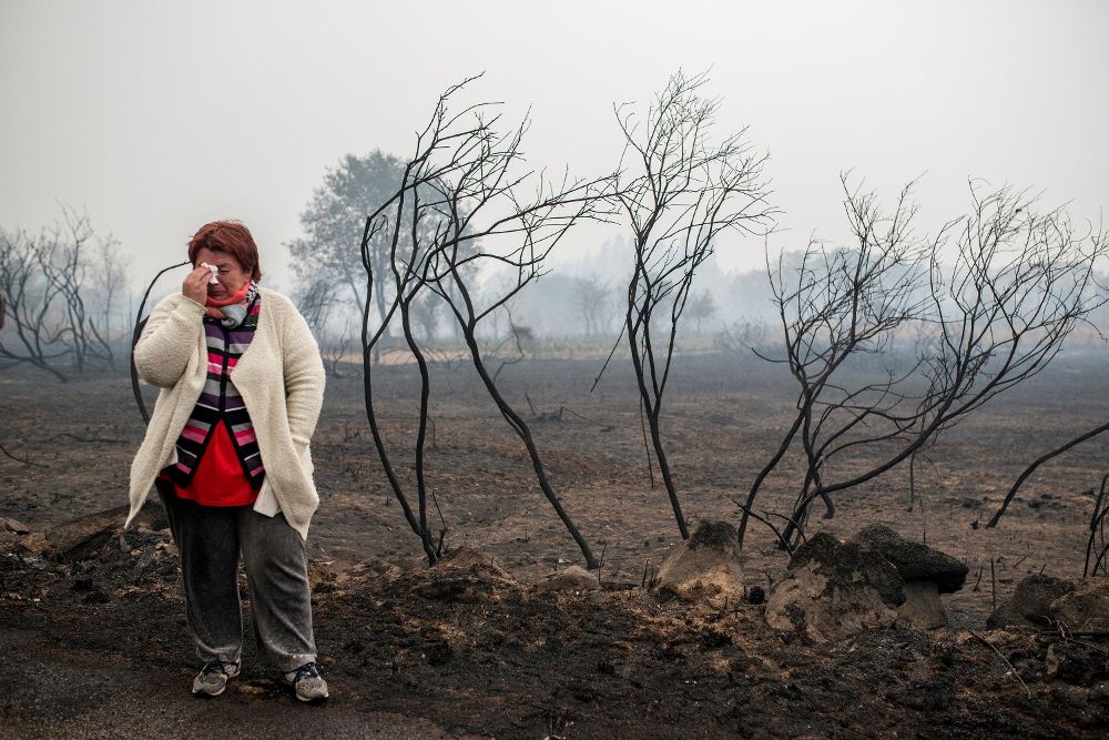 Una mujer llora ante el paisaje calcinado por el fuego, en la zona de Abelenda das Penas (Carballeda de Avia).