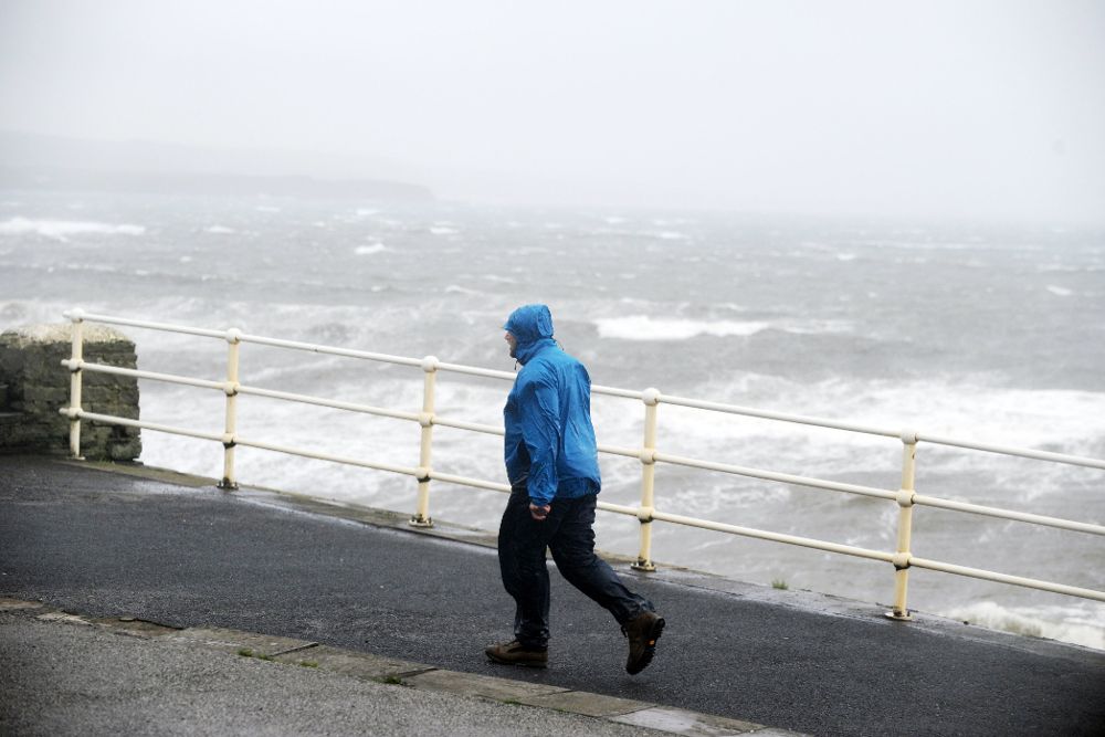 Un hombre camina junto al fuerte oleaje en la costa del Condado de Clare, Irlanda.