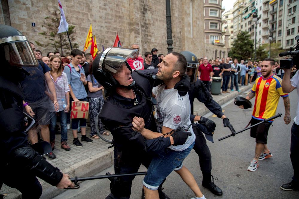 Agentes de la policía tratan de controlar a un joven durante la tradicional manifestación de entidades de izquierda y nacionalista del 9 d'Octubre llevada a cabo por el centro de Valencia.