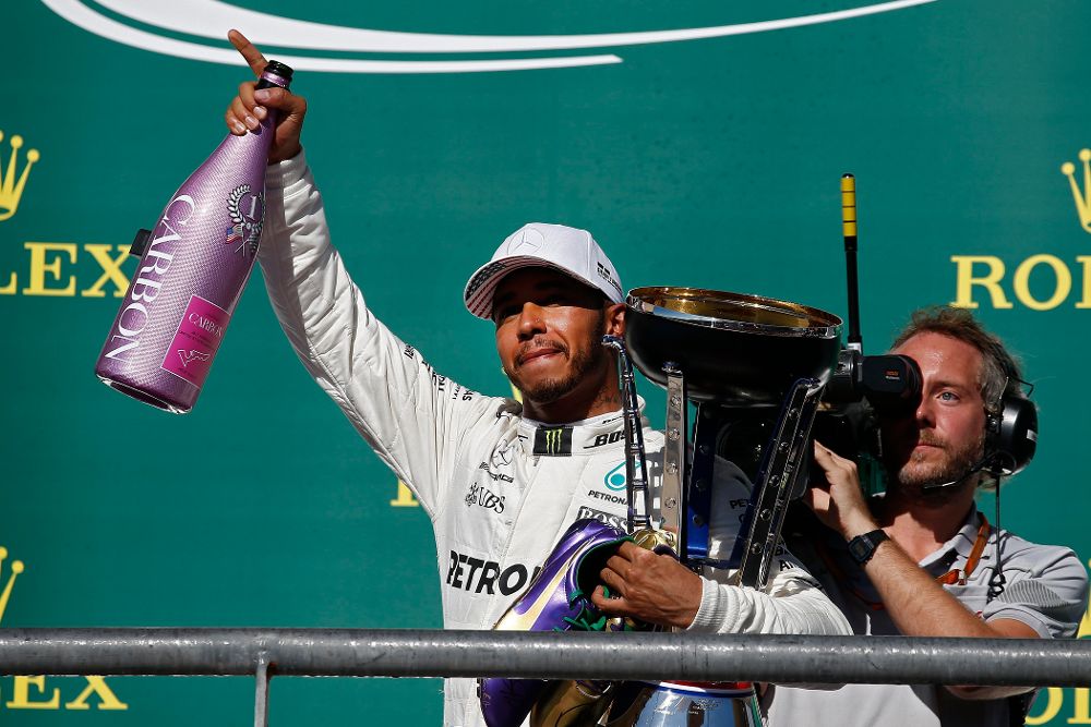 Lewis Hamilton celebra la victoria en el podio con su trofeo.