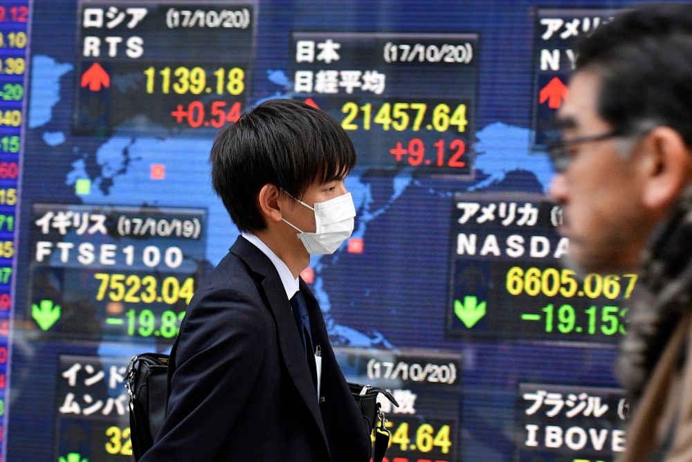 Un hombre pasa delante de un panel con los datos de la Bolsa de Tokio.