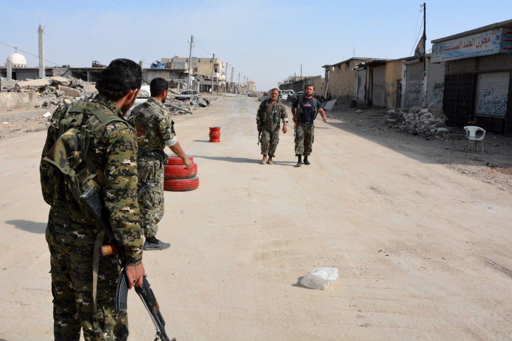 Combatientes de las Fuerzas Democráticas Sirias patrullan en medio de la ciudad destruida de Al Raqa.