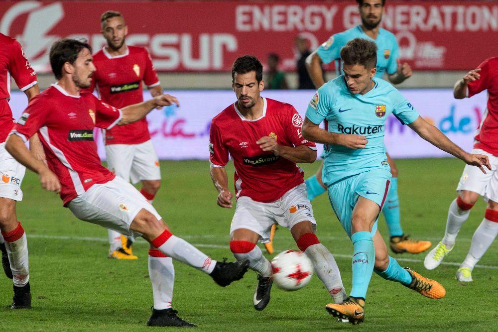 El centrocampista del F.C Barcelona Denis Suárez (d) intenta llevarse el balón ante los jugadores del Real Murcia, Antonio Escribano (i) y Pedro Orfila.