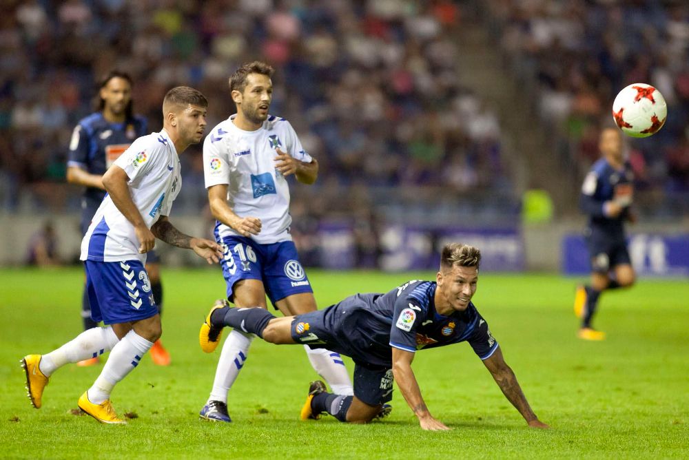 El centrocampista del RCD Espanyol Hernán Pérez (d) cae ante Nahuel (i) y Aitor Sanz, ambos del CD Tenerife, durante el partido de ida de dieciseisavos de final de la Copa de Rey que se disputa esta noche en el estadio Heliodoro Rodríguez López, en Tenerife.