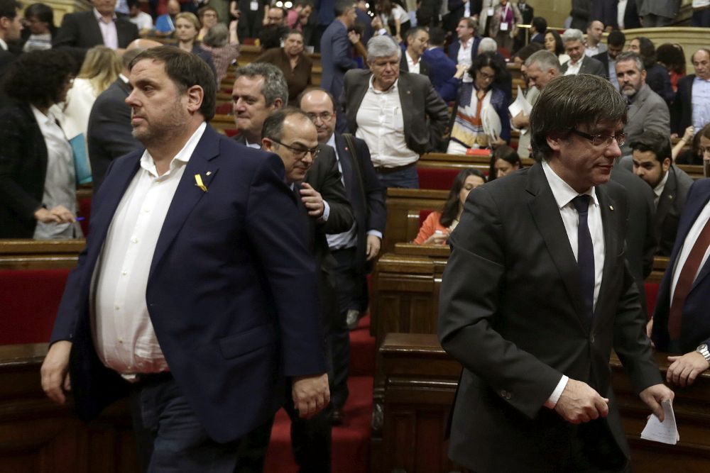 El presidente de la Generalitat, Carles Puigdemont, y el vicepresidente, Oriol Junqueras (i), abandonan el hemiciclo tras el pleno monográfico para abordar la respuesta a la aplicación del artículo 155 de la Constitución.