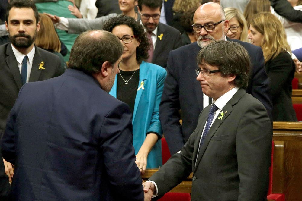 Puigdemont (d) y Oriol Junqueras (i) se saludan tras aprobarse en el pleno del Parlament la declaración de independencia.