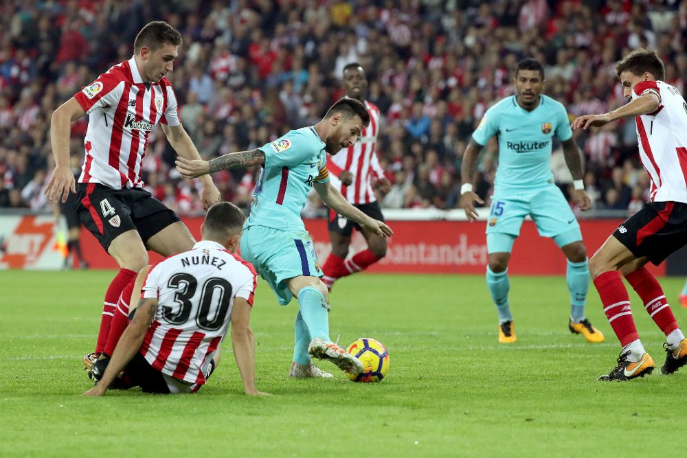 El delantero argentino del FC Barcelona, Leo Messi (3i), se lleva el balón ante los jugadores del Athletic, el francés Aymeric Laporte (i), Unai Núñez (2i) y Ander Iturraspe, durante el encuentro correspondiente a la décima jornada de primera división que disputan esta noche en el estadio de San Mamés, en Bilbao.