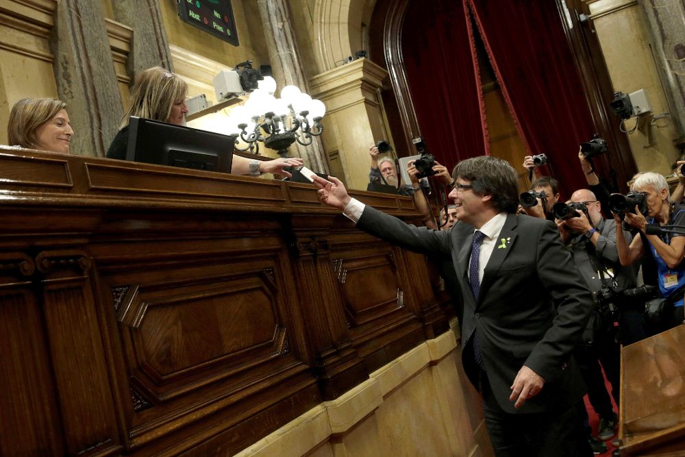 Carles Puigdemont entrega su voto a favor de la declaración de independencia a un miembro de la Mesa ante la mirada de la presidenta de la cámara catalana, Carme Forcadell (i).