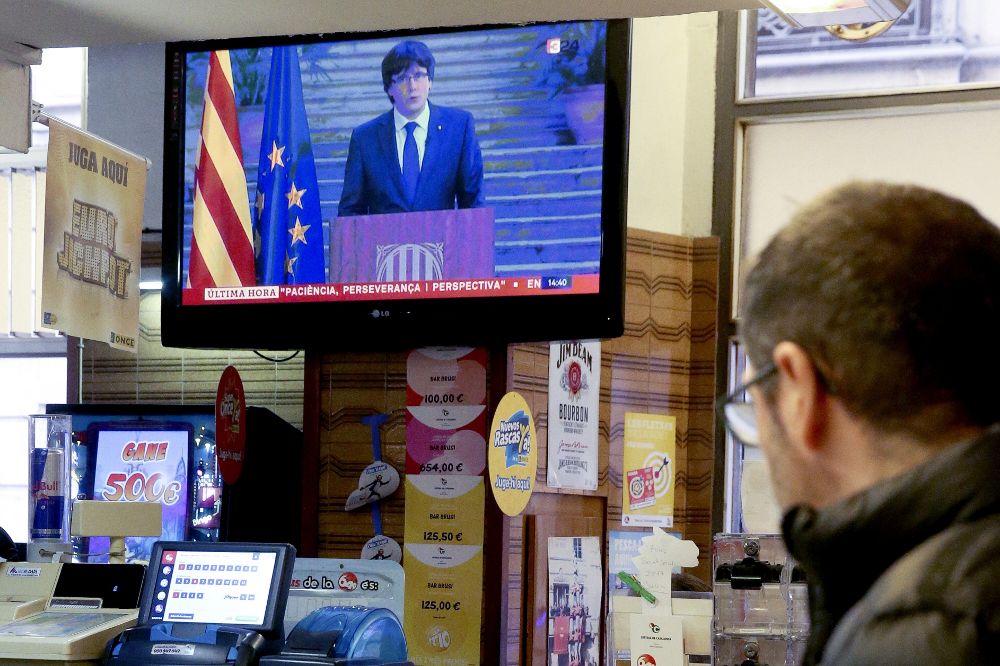 Un hombre sigue en la televisión de un bar una declaración de Carles Pigdemont.