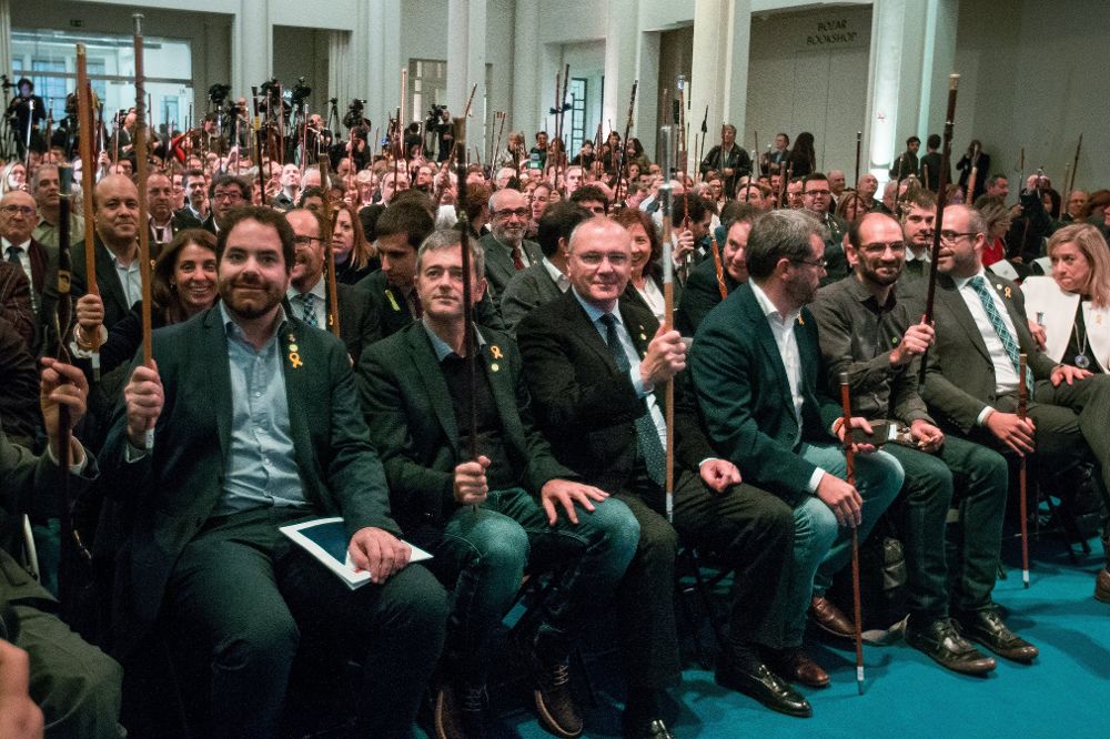 Varios alcaldes saludan al expresidente de la Generalitat catalana Carles Puigdemont (fuera de la imagen), durante el acto que 200 alcaldes independentistas celebran en Bruselas, Bélgica, el 7 de noviembre del 2017, para apoyar al cesado Gobierno catalán.