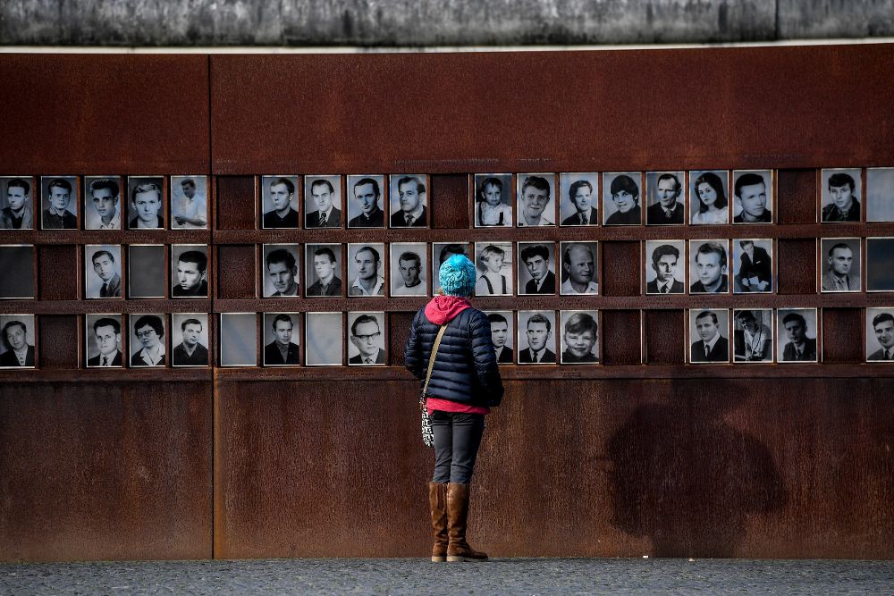 Una mujer observa las fotografías de personas muertas en el Muro de Berlín.