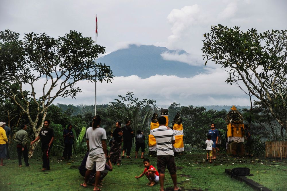 Residentes observan desde Karangasem, Indonesia, el cráter del volcán Agung que expulsa vapor.