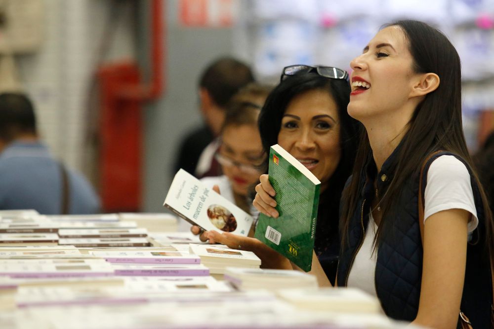 Visitantes observan libros expuestos durante de la Feria internacional del Libro de Guadalajara.