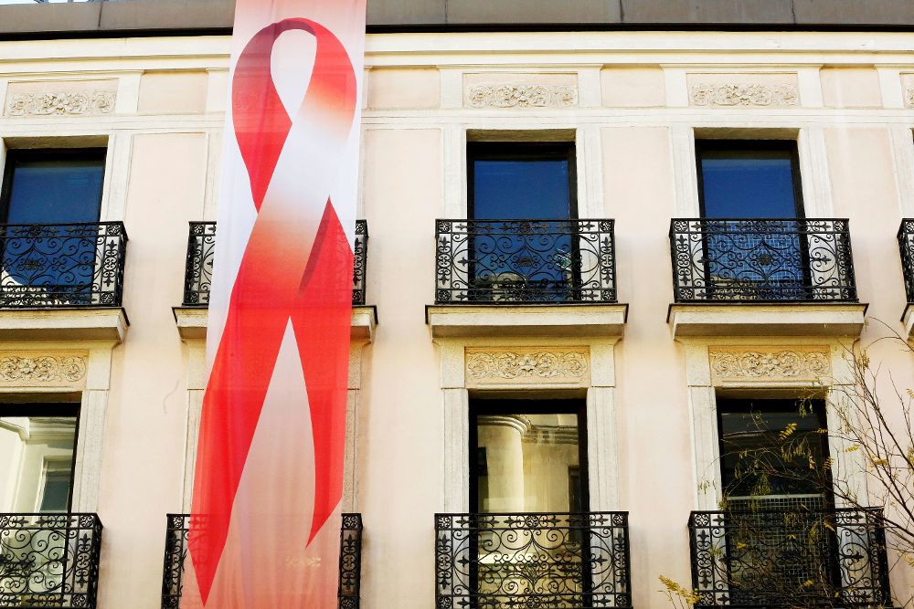 Fotografía facilitada por el PSOE del lazo rojo desplegado esta mañana en la fachada de Ferraz con motivo del Día Mundial de la lucha contra el SIDA.