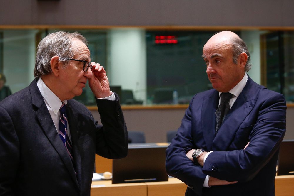 El ministro de Economía español, Luis de Guindos (dcha), conversa con su homólogo italiano, Pier Carlo Padoan, durante la reunión del Eurogrupo, en Bruselas.