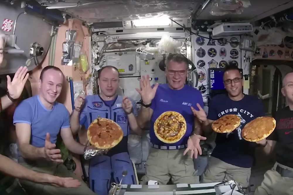 Paolo Nespoli (c) y sus compañeros cocinan pizzas a bordo de la Estación Espacial Inernacional (ISS), el 3 de diciembre de 2017.