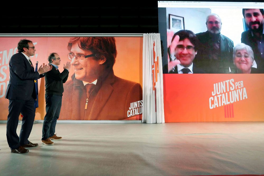 Los exconsellers y candidatos de JxSí Jordi Turull y Josep Rull (i) hablan por videoconferencia con el expresidente Puigdemont y los exconsellers Puig, Comín y Ponsatí, huidos en Bruselas.