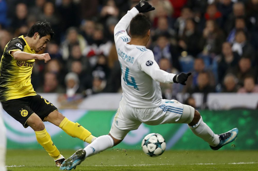 El delantero japonés del Borussia Dortmund Shinji Kagawa (i) dispara frente al brasileño Carlos Casemiro, del Real Madrid.