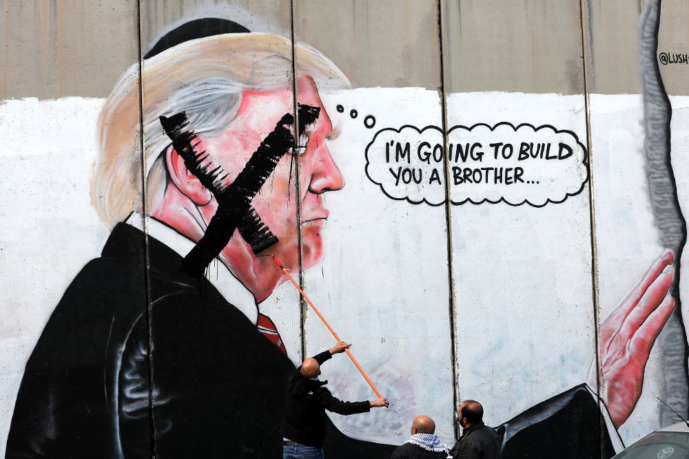 Palestinos pintan una "X" sobre el rostro del presidente estadounidense, Donald J. Trump, representado en un mural en el muro de separación israelí, en la localidad cisjordana de Belén, hoy, 7 de diciembre de 2017.