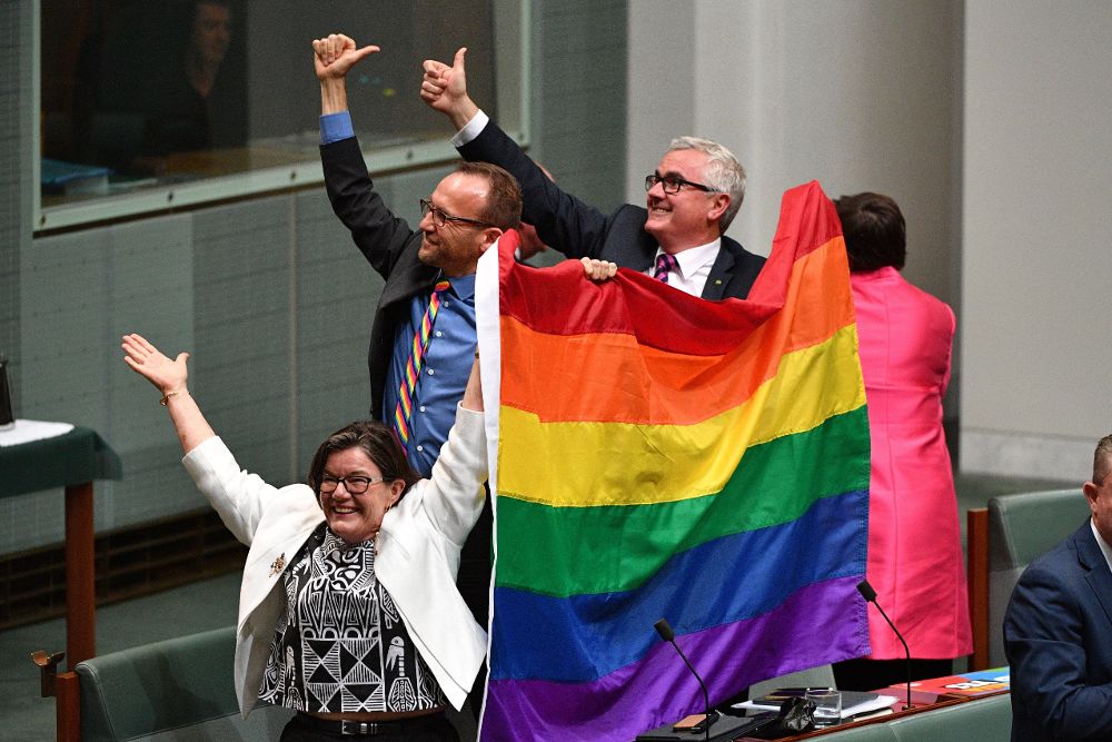 Los diputados Cathy McGowan (i), Adam Brandt (c) y Andrew Wilkie (d) celebran la aprobación del matrimonio entre personas del mismo sexo en el Parlamento en Canberra.