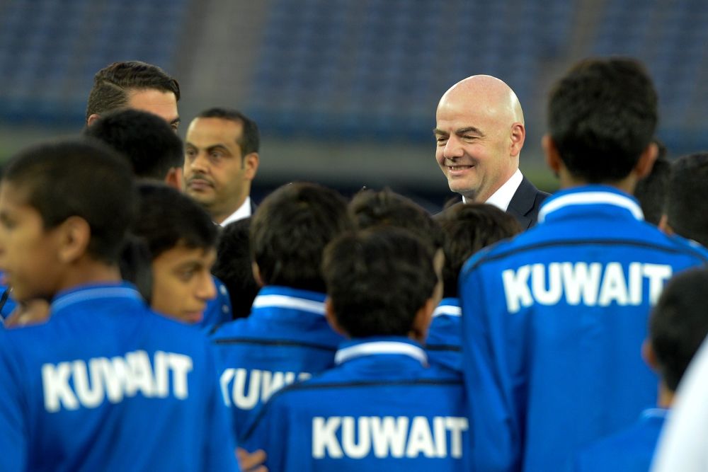 El presidente de la FIFA, Gianni Infantino (c-d), habla con jóvenes jugadores de fútbol durante su visita a Kuwait.
