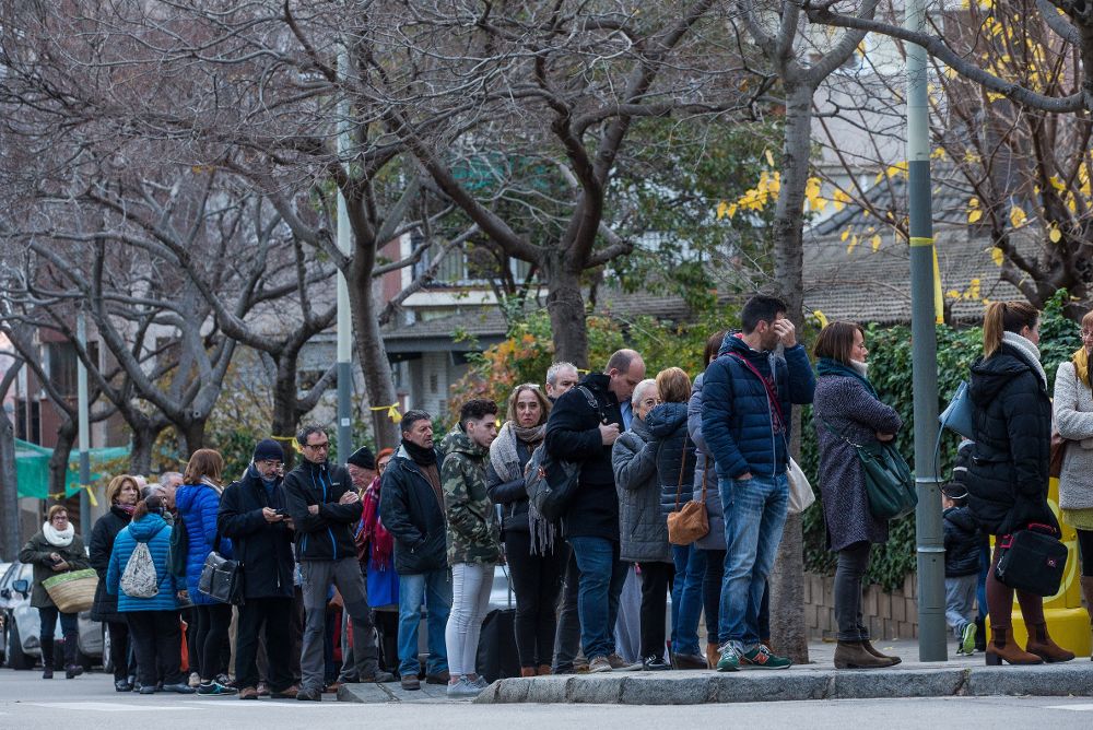 Una fila de ciudadanos esperan para votar en el exterior del colegio electoral Narcís Monturió de Barcelona.