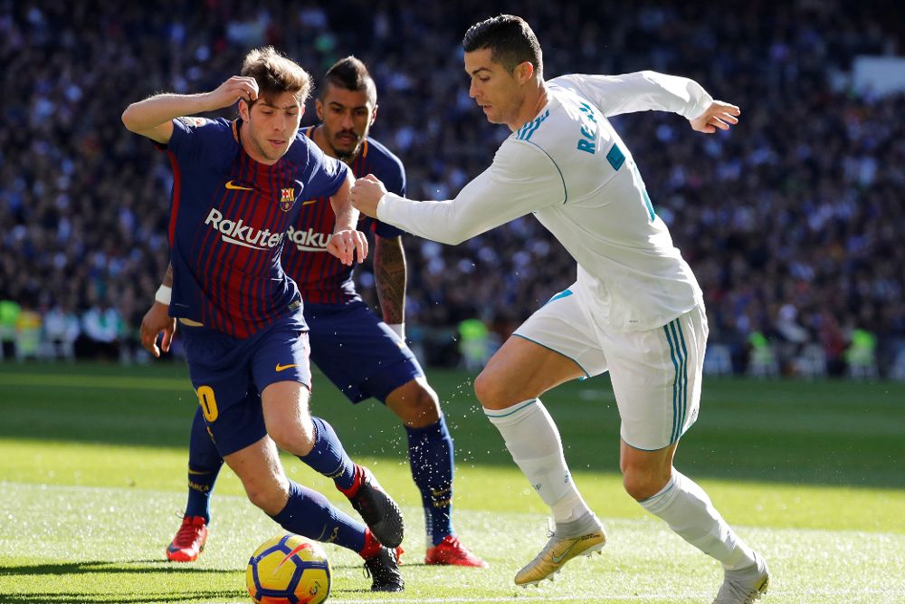 Cristiano Ronaldo (d), intenta controlar el balón ante el centrocampista del FC Barcelona, Sergi Roberto.
