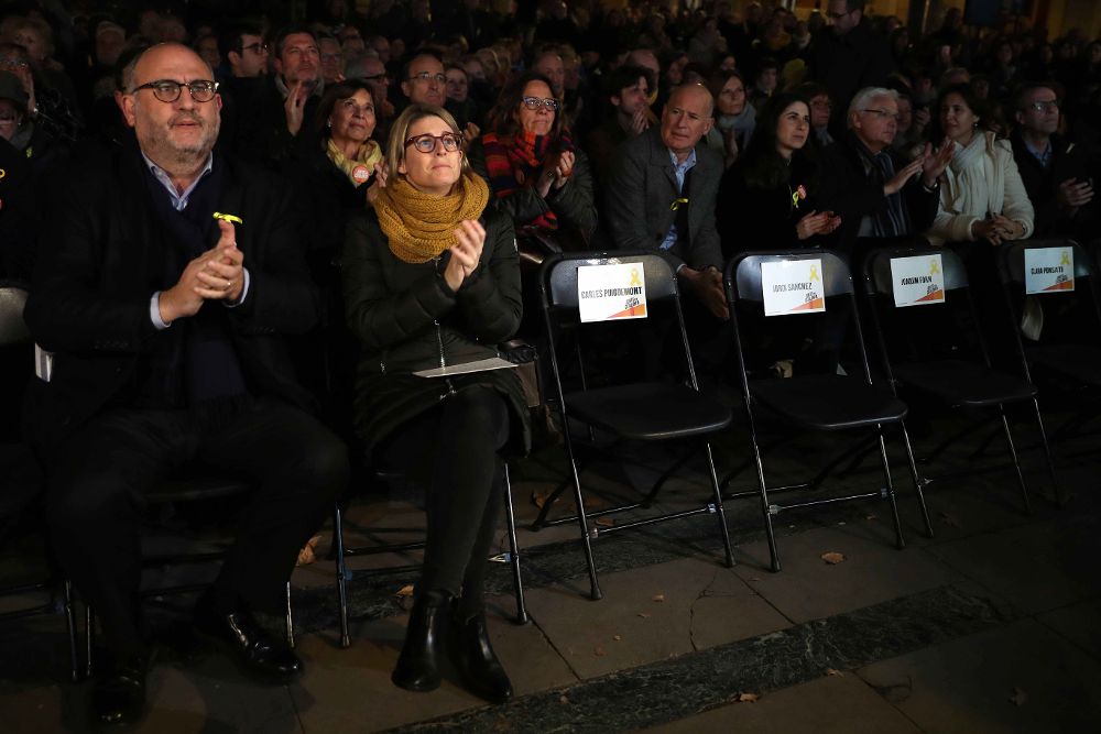 Los candidatos del Junts per Catalunya Eduard Pujol y Elsa Artadi, junto a las sillas vacías en recuerdo a Carles Puigemont, Jordi Sánchez y otros presos y políticos en Bruselas.
