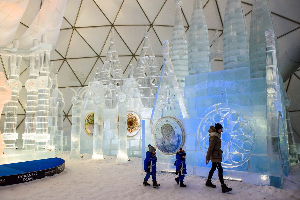 Unos visitantes pasan junto a una escultura de hielo, inspirada en la Sagrada Familia de Barcelona (España), expuesta en la cúpula del complejo de los montes Tatras en Hrebienok (Eslovaquia), el 20 de diciembre de 2017.