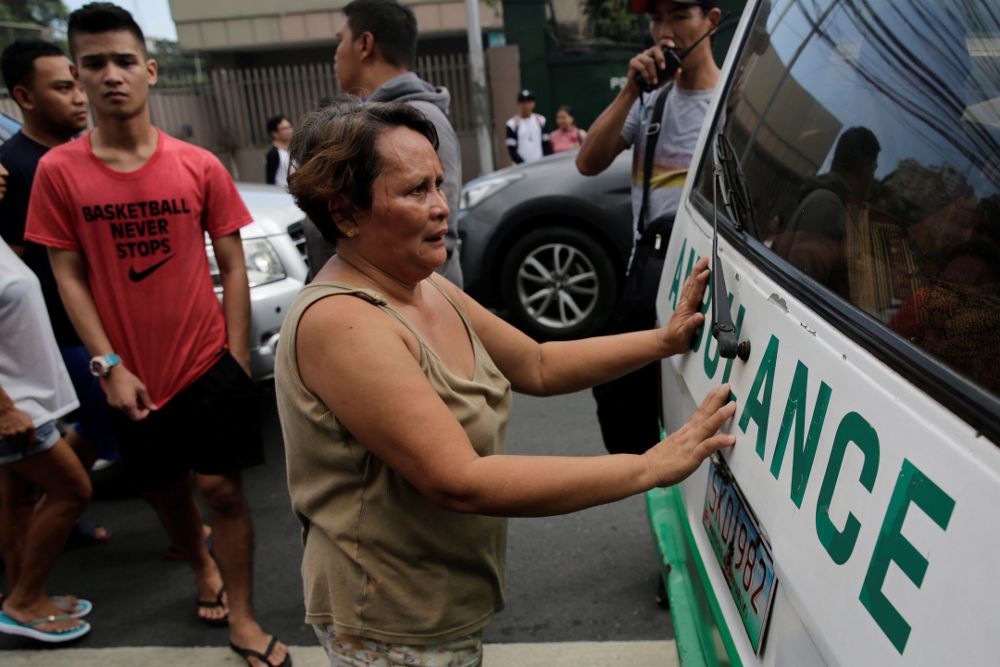 Varios filipinos rodean una ambulancia que transporta el cadáver de un persona tiroteada en un "asesinato extrajudicial" en Manila.