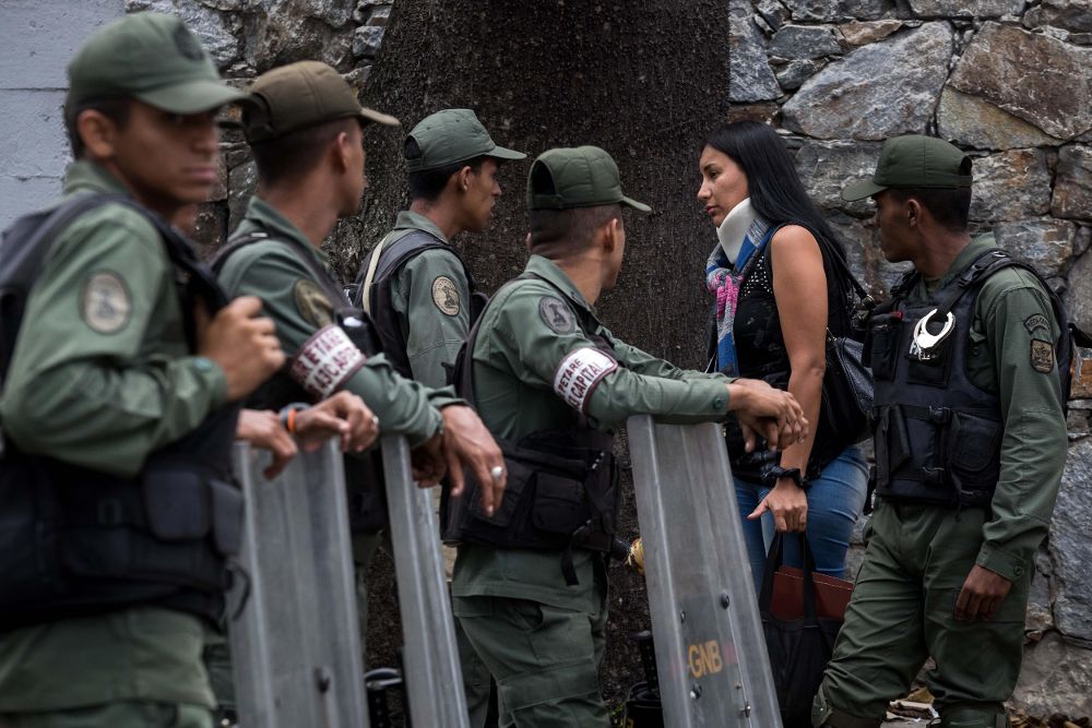 Miembros de la Guardia Nacional Bolivariana custodian las inmediaciones de la morgue mientras entra Lady Ramírez, hermana de Andreína Ramírez, una de las siete personas que murieron en el enfrentamiento con la policía y militares.