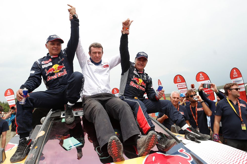 El español Carlos Sainz (d) (Peugeot) celebra con su copiloto y compatriota Lucas Cruz (i) y Bruno Famine (c), manager del equipo Peugeot, luego de ganar el Dakar 2018 hoy, sábado.