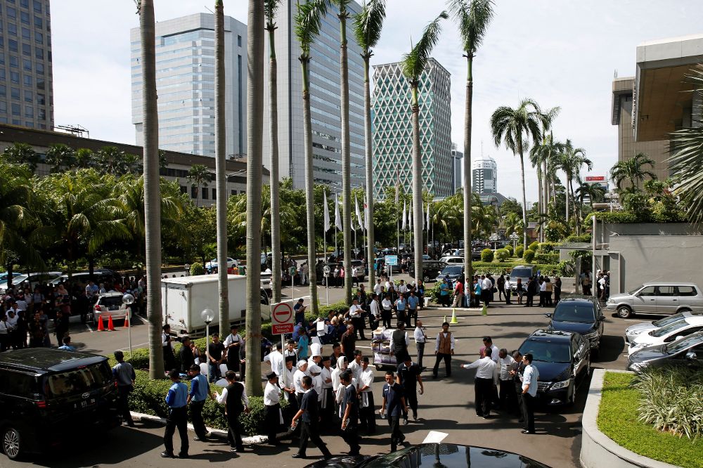 Varios trabajadores aguardan fuera de un edificio en Yakarta.