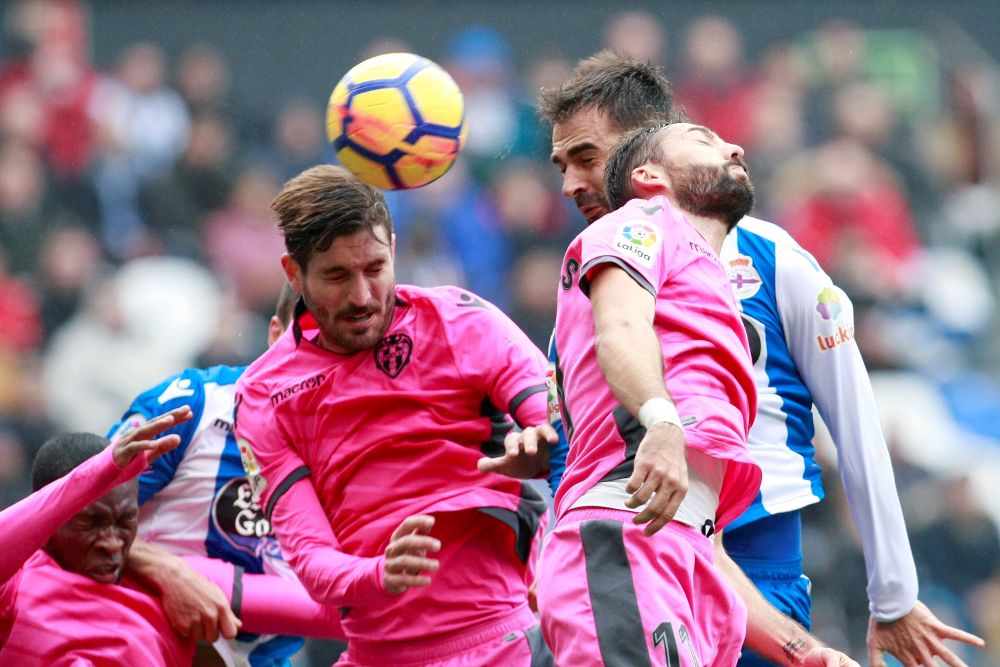 El delantero del Deportivo Adrián López (d), pelea un balón con el jugador del Levante José Campaña (i).