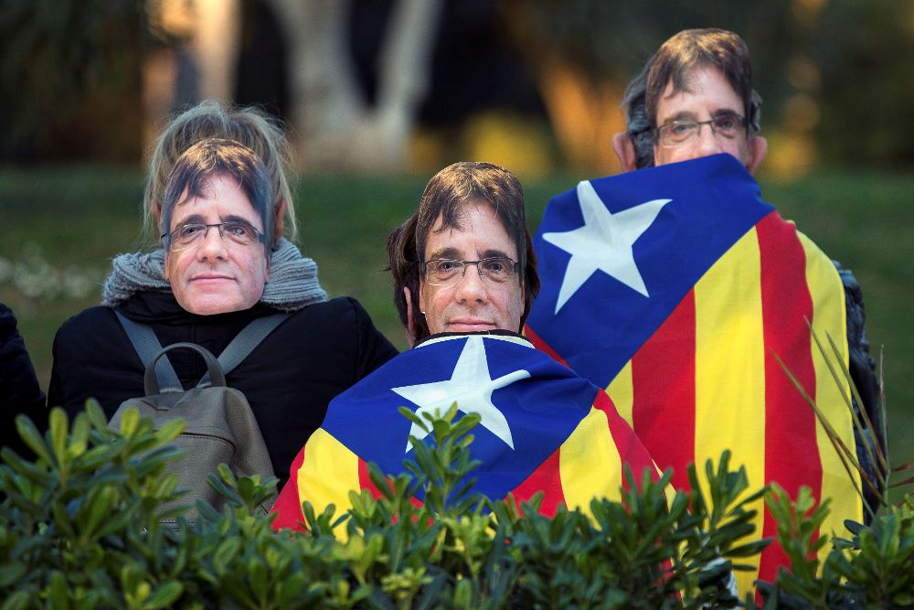 Manifestantes independentistas con caretas que llevan la cara de Puigdemont ante el Parlament durante la frustrada investidura de este.