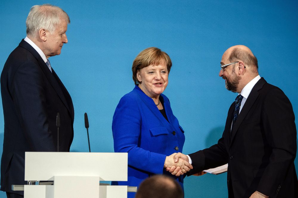 Merkel (c) estrecha la mano de Schulz en presencia de Horst Seehofer.