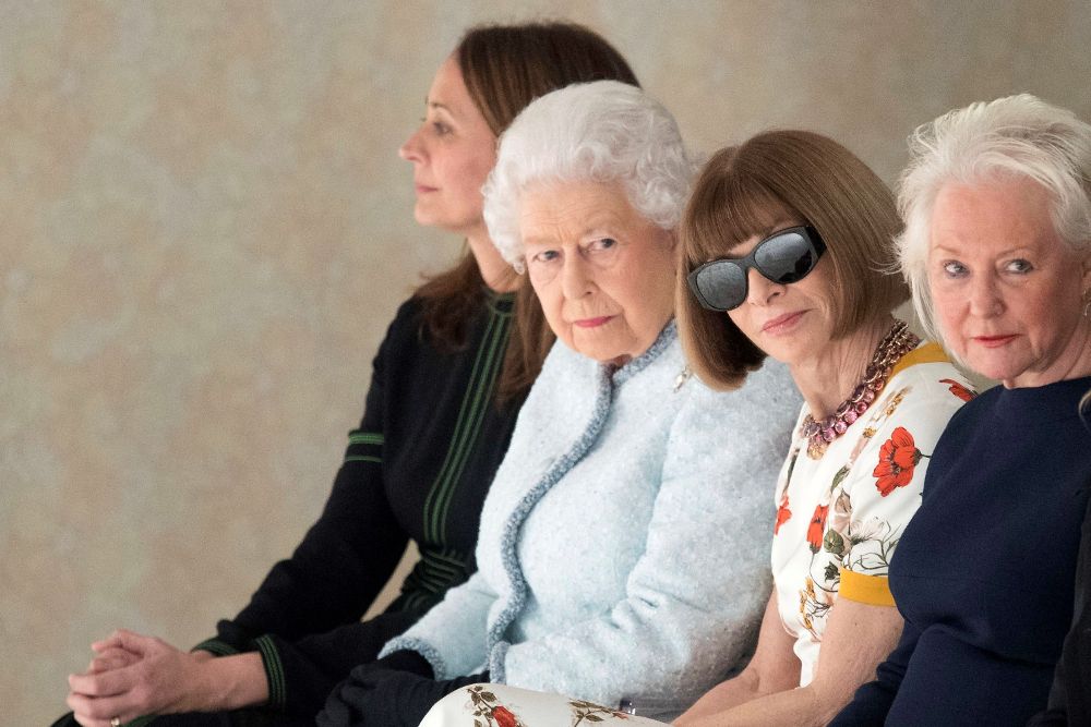 La reina Isabel II (2i), la editora de la revista Vogue, Anna Wintour (2d), y la directora del British Fashion Council, Caroline Rush (2d) asisten al desfile del diseñador británico Richard Quinn.