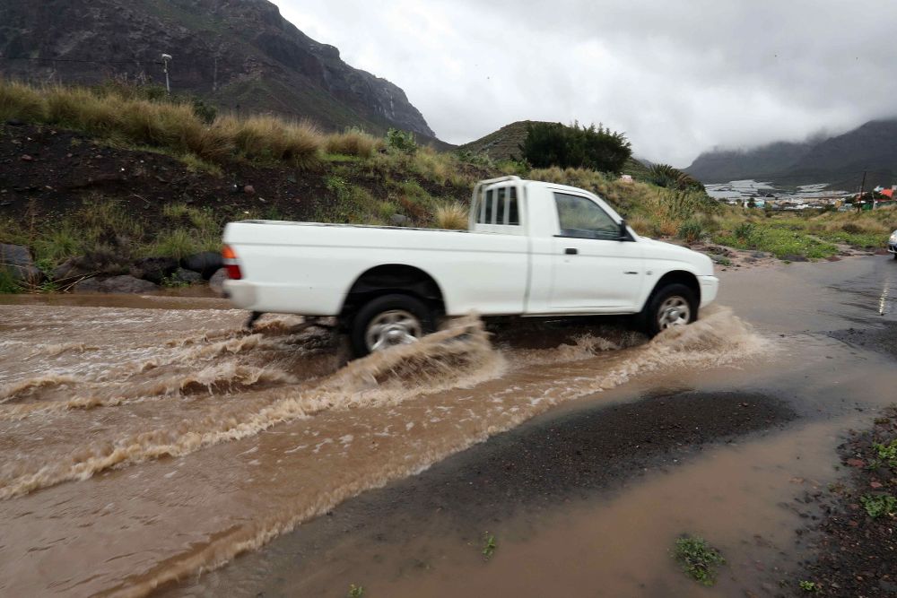 Un vehículo atraviesa una carretera inundada por las lluvias en el municipio de La Aldea de San Nicolás, en el oeste de la isla de Gran Canaria.