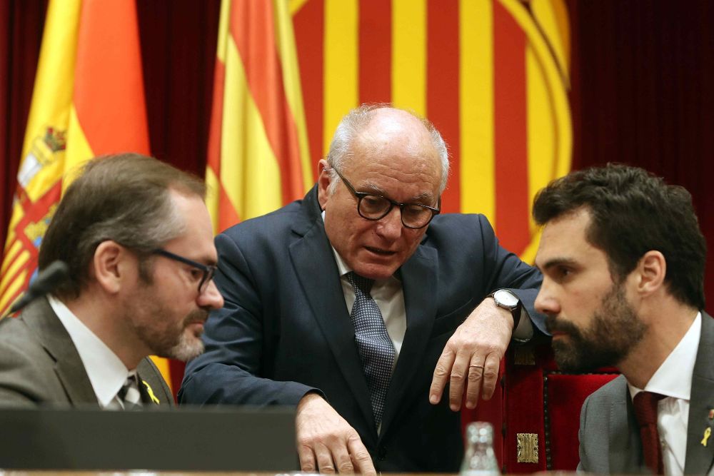 El presidente del Parlament, Roger Torrent (d), y el vicepresidente primero, Josep Costa (i), hablan con el letrado de la cámara, Xavier Muro (c), durante el pleno del Parlament.