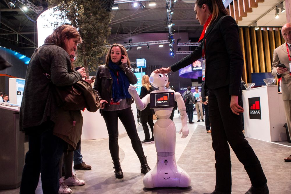 Varios visitantes interactuan con un robot en uno de los expositores del Mobile World Congress.