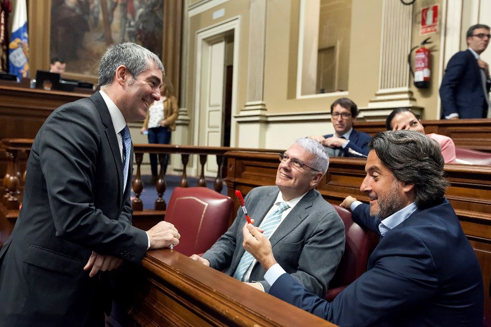 El presidente del Gobierno de Canarias, Fernando Clavijo (i), bromea con los diputados del PSC-PSOE, Gustavo Matos (d) y Manuel Marcos Pérez, con los bolígrafos utilizados por ambos grupos parlamentarios para la votación de la RTVC.